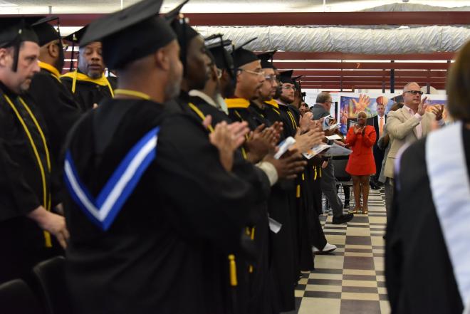 The processional — caps, gowns, and applause inside the facility